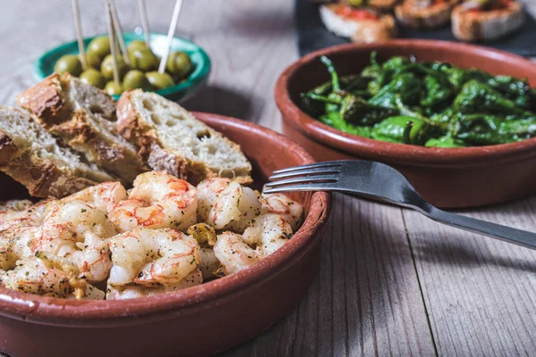 Tahta bir masanın üstünde birkaç tapas tabağı var.