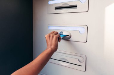Tanınmayan afro bir kadın ATM 'ye kredi kartı sokuyor.