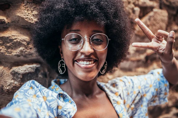 Afrikalı bir kadın selfie çekiyor ve parmaklarıyla zafer işareti yapıyor.