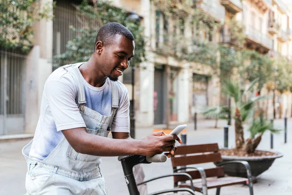 Привабливий африканський юнак користується своїм розумним телефоном на вулицях Барселони. — стокове фото