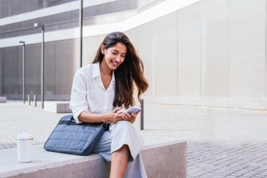Genç Hintli bayan avukat mahkemeye girmeden önce akıllı telefonunu kullanıyor.