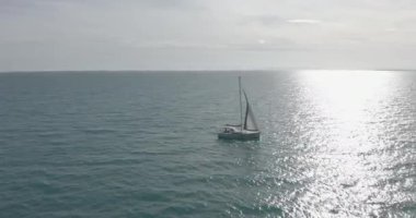 Açık deniz anteninde beyaz yelkenli güneş yatları. Güneşli yaz gününde deniz manzarası. Okyanus körfezinde yelkenlilerde yatçılık. Sakin ve rahat bir yaşam tarzı var. Sinematik dingin manzara.