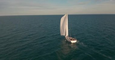 Açık deniz anteninde beyaz yelkenli güneş yatları. Güneşli yaz gününde deniz manzarası. Okyanus körfezinde yelkenlilerde yatçılık. Sakin ve rahat bir yaşam tarzı var. Sinematik dingin manzara.