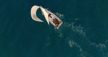 Açık deniz anteninde beyaz yelkenli güneş yatları. Güneşli yaz gününde deniz manzarası. Okyanus körfezinde yelkenlilerde yatçılık. Sakin ve rahat bir yaşam tarzı var. Sinematik dingin manzara.