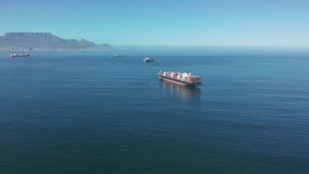 一艘大型集装箱船，在南非开普敦港口附近运送货物。集装箱船载着货物过海.交通。交付。物流。Aerial 4K shot. — 图库视频影像