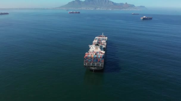 남아프리카 공화국의 카페 타운 항구 근처에서 화물을 운송하는 대형 컨테이너 선박. 컨테이너 선박은 바다를 가로질러 화물을 운반 한다. 교통. 배달이요. 곡물식이요. 공중 4K 샷. — 비디오