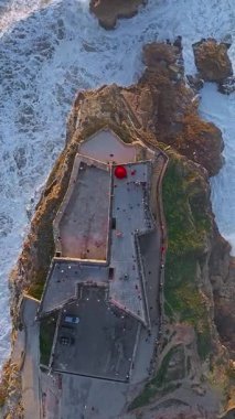  Nazare Deniz fenerinin hava manzarası. Dünyanın en büyük dalgaları çarpıcı deniz fenerinin kayalarına çarpıyor. Portekiz 'de Nazare Deniz Feneri manzarası.