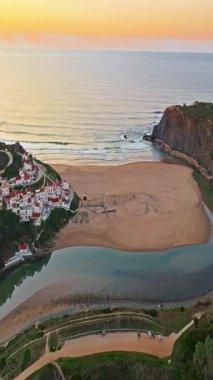  Yel değirmeni ve pitoresk çatıları olan küçük köyün havadan görünüşü, Aldatmaca, Portekiz.