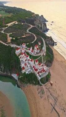  Yel değirmeni ve pitoresk çatıları olan küçük köyün havadan görünüşü, Aldatmaca, Portekiz.