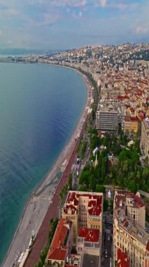  Güneşli bir günde, hareketli bir sahil yürüyüşü manzarası. Nice, Fransa 'da güzel bir manzara. Palmiye ağaçları, eski kasabadaki eski evler gök mavisi deniz ve yeşil tepeler. Fransız Rivierasında yaz.