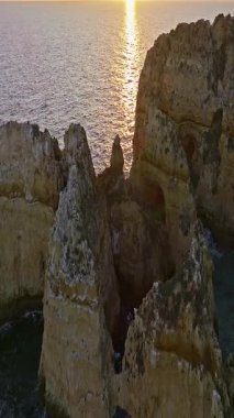  Günbatımında Ponta da Piedade, Lagos, Portekiz 'deki dramatik uçurumların ve deniz fenerinin havadan görünüşü.