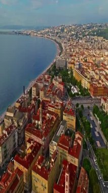  Güneşli bir günde, hareketli bir sahil yürüyüşü manzarası. Nice, Fransa 'da güzel bir manzara. Palmiye ağaçları, eski kasabadaki eski evler gök mavisi deniz ve yeşil tepeler. Fransız Rivierasında yaz.