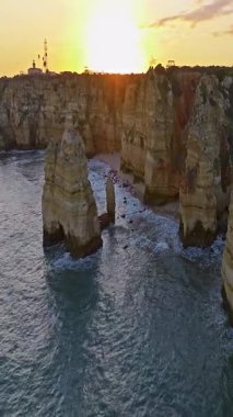  Günbatımında Ponta da Piedade, Lagos, Portekiz 'deki dramatik uçurumların ve deniz fenerinin havadan görünüşü.