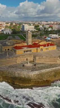  Arka planda ünlü bir köprü olan Portekiz 'deki bir kalenin insansız hava aracı görüntüsü. Portekiz, Carcavelos sahilinden deniz feneri kulesi olan Aziz Julian Kalesi. Carcavelos 'taki Atlantik okyanus dalgaları plajı.