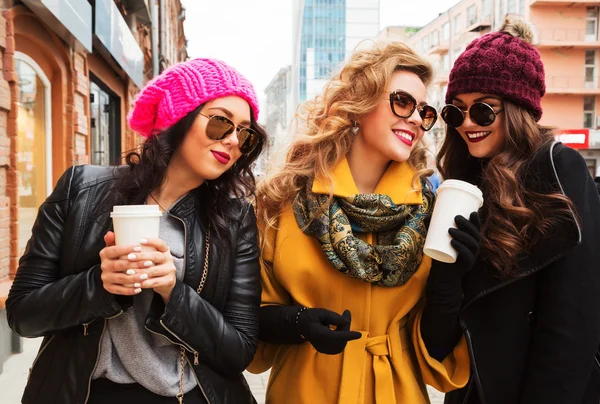 Outdoors lifestyle  fashion portrait of company cheerful pretty girls friends drinking coffee. Walking in the city