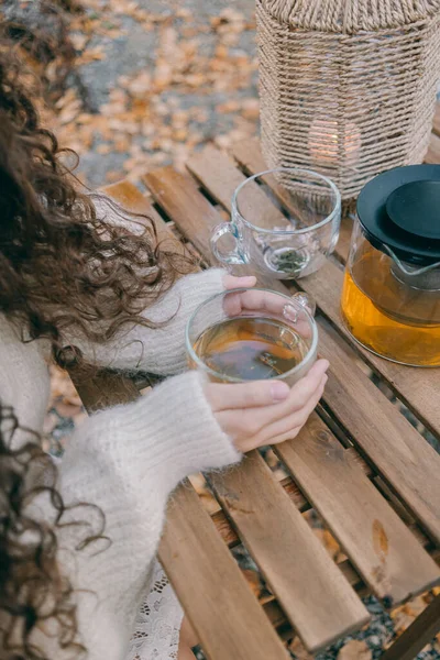 Kız açık havada cam bardağa çay dolduruyor.