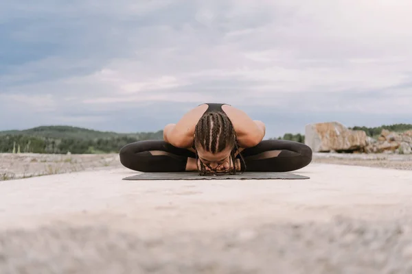 Yoga girl in black suit doing yoga exercises at sunset