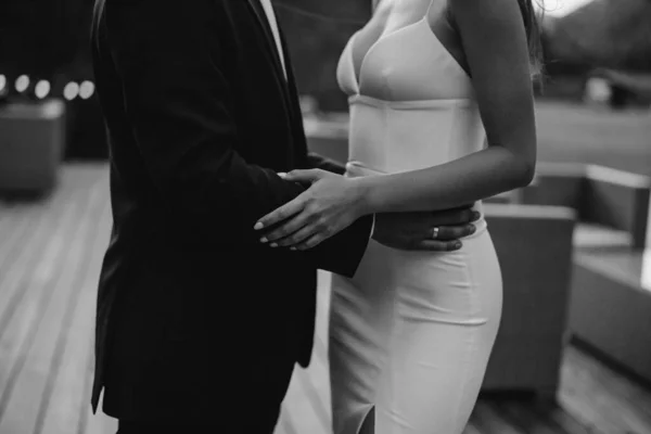 Takım elbiseli damat geline sarılıyor.