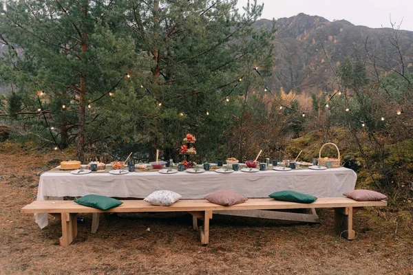 Sonbaharda ağaçların arasında sunulan düğün masası.