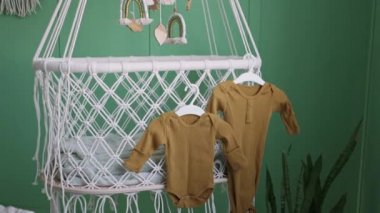 Bebek kıyafetleri oyuncaklarla beşikte asılı.