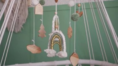 Bebek kıyafetleri oyuncaklarla beşikte asılı.