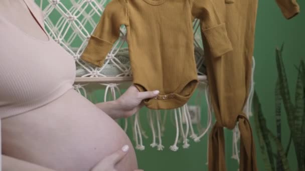 Jong Zwanger Meisje Hangt Baby Kleding Een Wieg Met Speelgoed — Stockvideo
