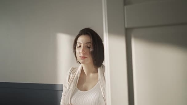 穿着白色内裤和白衬衫的怀孕少女站在白墙边晒太阳 — 图库视频影像