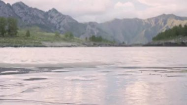 Gün batımında Altai 'deki dağların arasında mavi bir nehrin üzerinde İHA ile uçmak