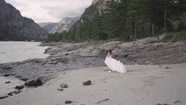 Een Bruid Een Trouwjurk Vliegend Wind Staat Een Rotsachtige Rivieroever — Stockvideo