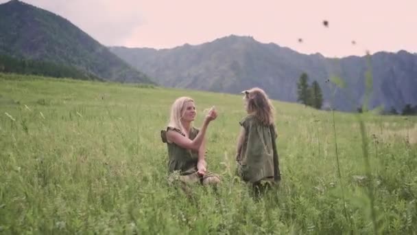 阿尔泰黄昏时分 年轻的母亲带着她的小女儿在山中的一片绿地上 — 图库视频影像