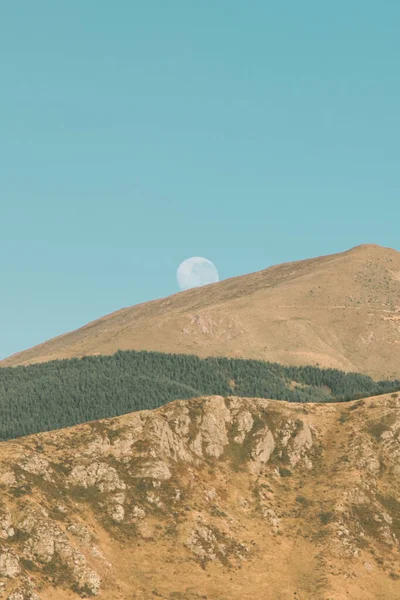Queenstown, Fiordland, Yeni Zelanda yolundaki tepelerin ardında saklanan ay.