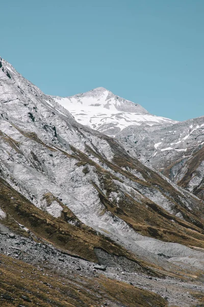 Dağın arka planında karlı tepeler olan kayalık tarafı, Rees-Dart Track, Yeni Zelanda 