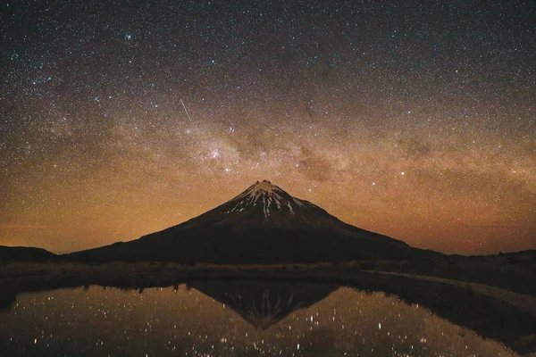 Poukakai Gölü 'ndeki Taranaki Dağı' nı gece gökyüzü ve kayan yıldızla yansıtmak, Egmont Ulusal Parkı, Yeni Zelanda 