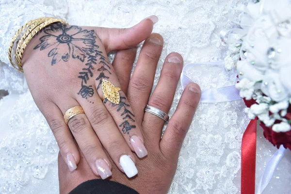 Hands of newlyweds with wedding rings and bridal bouquet. Henna drawing on the skin, not a tattoo. High quality photo