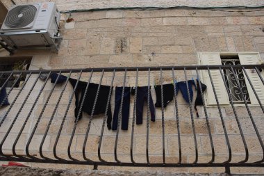 Kudüs İsrail 27 Mart 2021: Kurutma ipinde siyah elbiseli balkon, evde taş duvar, klima. Yüksek kalite fotoğraf