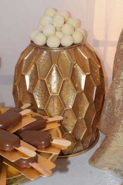 Masasında yuvarlak kurabiye topları, bayram yemeği ve tatlı olan altın kaplama dekoratif vazo. Yüksek kalite fotoğraf