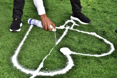 Genç adam yeşil çimenlere köpük bir kalp çiziyor. Yüzü yok, alt tarafı. Yüksek kalite fotoğraf