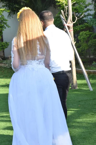 the groom and the bride in white clothes stand with their backs, the woman has long hair. High quality photo