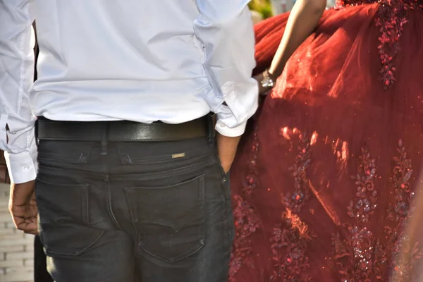 the newlyweds stand with their backs, a man in trousers and a white shirt, a girl in a red wedding dress. High quality photo