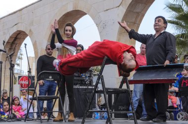 Beer-Sheva, ISRAEL - March 5, 2015: Magician performs on the street scene hypnosis session with the girl in red -Purim clipart