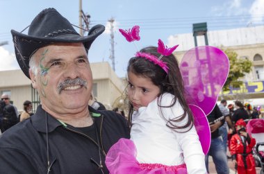 Beer-Sheva, İsrail-5 Mart 2015: bıyıklı, siyah ve siyah kovboy şapkası şenlikli bir makyaj ile yaşlı bir adam ve küçük bir kız pembe elbise - Purim tutar