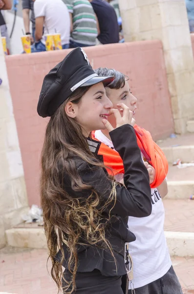 Beer-Sheva, ISRAEL - March 5, 2015:Girl with beautiful long hair in black police cap standing in profile with teen boys -Purim — Stock Photo, Image