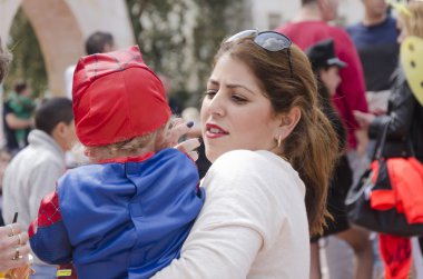 Beer-Sheva, İsrail-5 Mart 2015: Genç bir anne ile bebeği Purim yedekler bir kırmızı şapkalı portresi