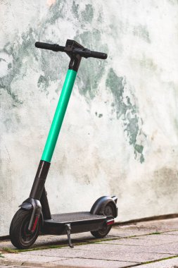 Elektrikli scooter parlak duvar zemininde duruyor. Mobil uygulamalı E-scooter ya da kick scooter. Modern, ekolojik, çevre dostu şehir ulaşımı. Şehirde yaz mevsimi. Boşluğu kopyala, kapat