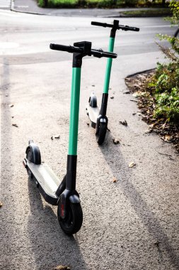 Park alanında sokakta duran elektrikli scooter 'lar. Mobil uygulamalı E-scooter ya da kick scooter. Modern, ekolojik, çevre dostu şehir ulaşımı. Şehirde yaz mevsimi. Boşluğu kopyala, kapat