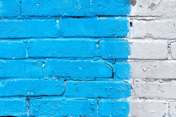 Blue and white brick wall detail texture background. Old, painted, weathered and cracked bricks with concrete and stucco. Stripes on house wall. Close up, copy space