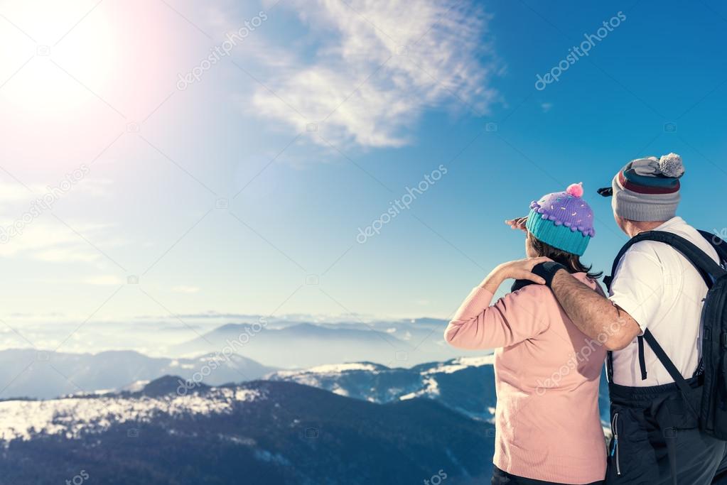 Middle aged couple looking away on the top of the mountain