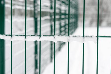 Metal çitlere yakın çekim. Bölgenin çitleri, yeşil çitler. Taze karla kaplı.