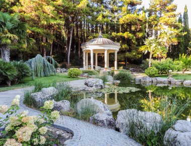 Yeni Athos, Abhazya. Güneşli bir günde, şehir parkındaki gölette beyaz çardak.