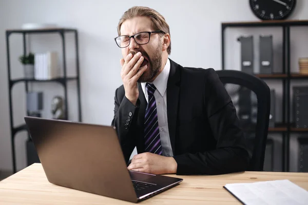 Empresario bostezando mientras está sentado en la oficina — Foto de Stock